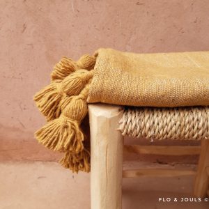plaid à pompons marque flo&jouls en laine tissé a la main au maroc marrakech par des artisans pour une décoration bohème sur un canapé ou un lit